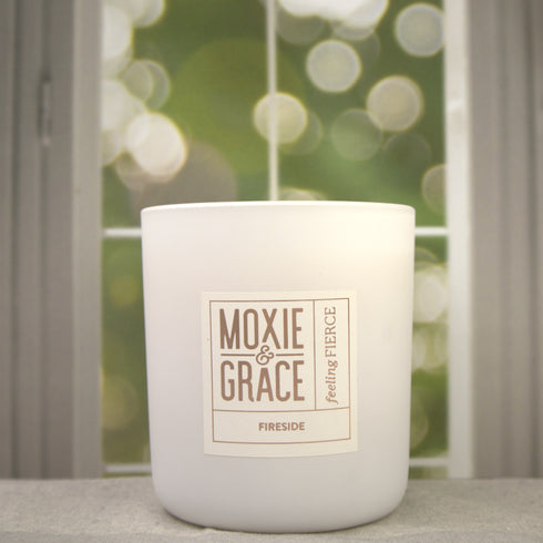 Fireside 12oz Candle in White by Moxie & Grace — a warm, smoky blend of cedarwood, sandalwood, birch, and smoked amber