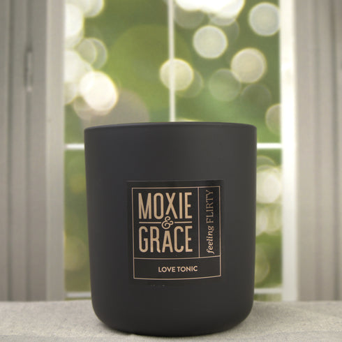 Love Tonic 12oz Candle in Black by Moxie & Grace — a sweet fruity-floral blend of apple, peach, cherry blossom, hydrangea, and vanilla